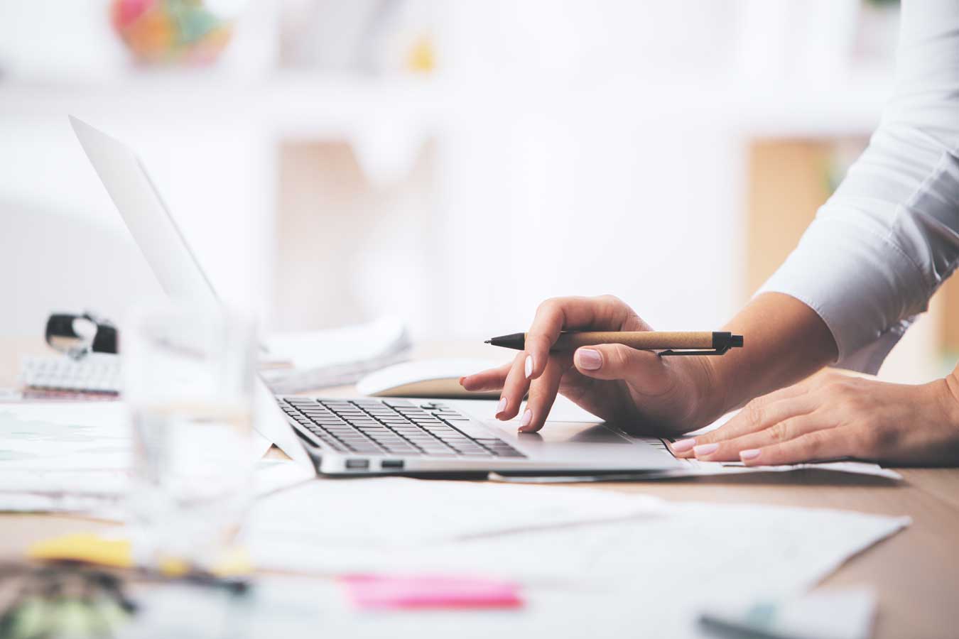 Side View Of Businesswoman's Hands Using Laptop Computer Placed On Messy Office Desktop